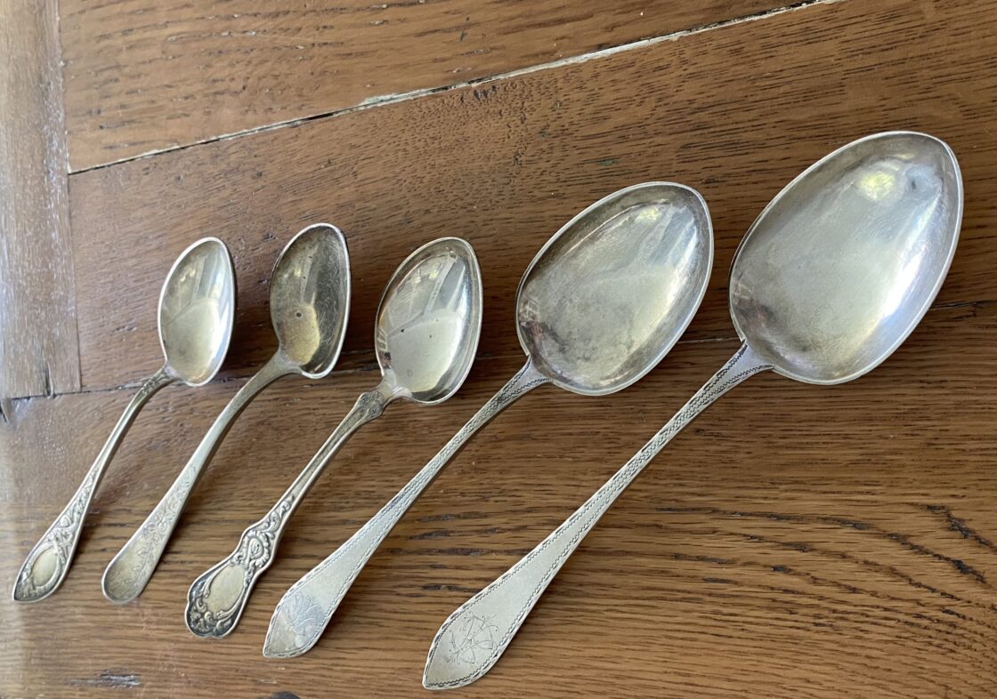 Five silver spoons on a wooden surface