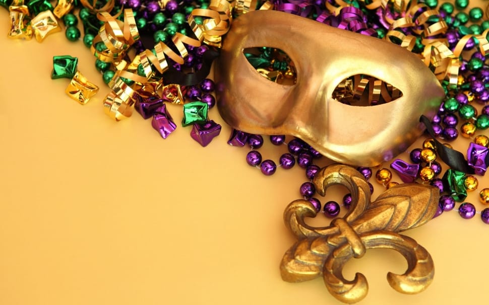 A gold face mask with jewels on a yellow background