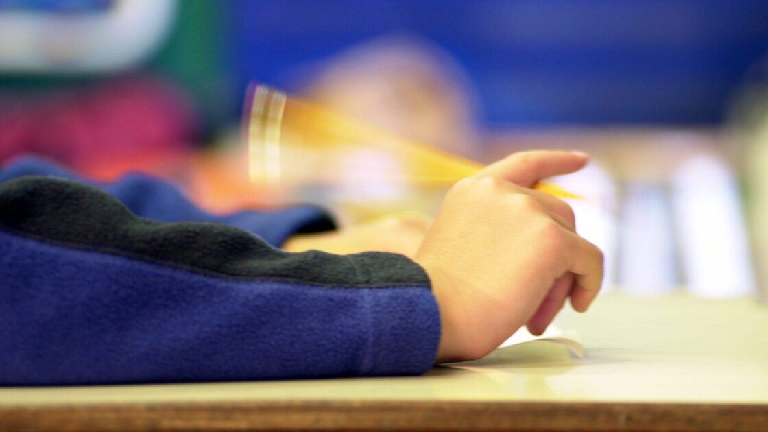 Arm of child wearing long sleeves with shaking pencil