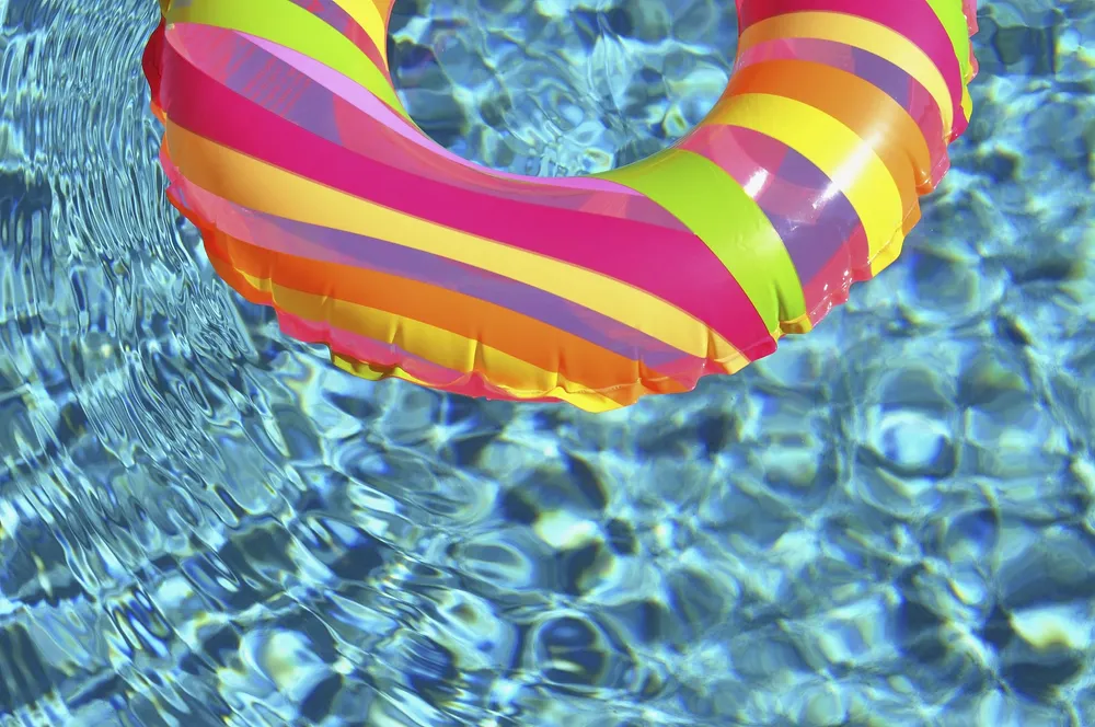 A rainbow ring flotation device in an aqua swimming pool with a rippled surface