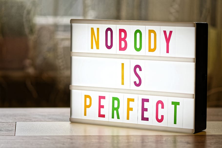 A white light board with the words “Nobody is perfect” written on it in a variety of bright colours.