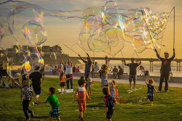 Adults and children at a party with giant bubbles