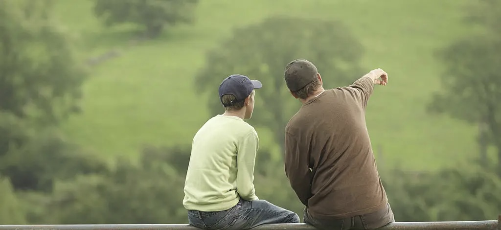 An adult and child sitting and pointing at something