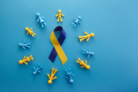 Blue and yellow toy figures around a blue and yellow charity ribbon representing Down Syndrome